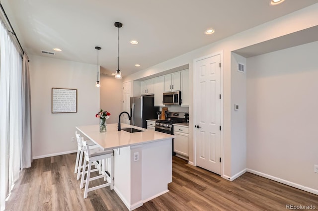 24374 E 42nd Ave, Aurora, CO 80019 - kitchen with appliances with stainless steel finishes, dark wood-style flooring, a kitchen island with sink, a sink, and a breakfast bar