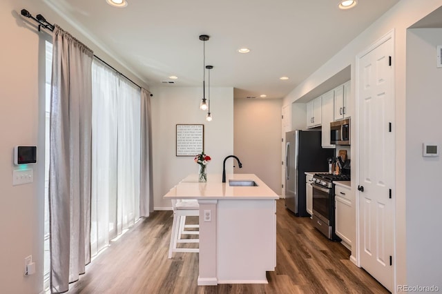 24374 E 42nd Ave, Aurora, CO 80019 - kitchen featuring appliances with stainless steel finishes, a sink, dark wood-style flooring, a kitchen breakfast bar, and recessed lighting