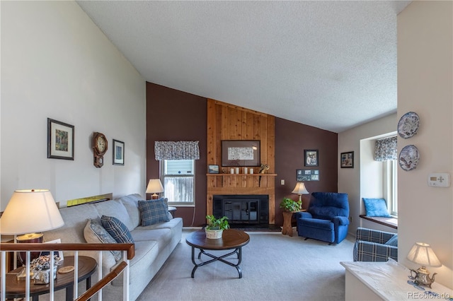 living area featuring carpet floors, a textured ceiling, a glass covered fireplace, and high vaulted ceiling