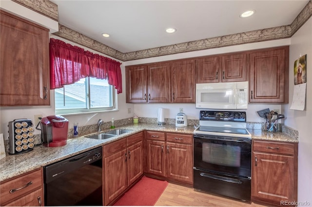 kitchen featuring light stone countertops, a sink, light wood finished floors, recessed lighting, and black appliances