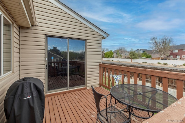 wooden terrace featuring area for grilling, a residential view, and outdoor dining area