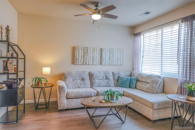 living area featuring baseboards, ceiling fan, wood finished floors, and visible vents