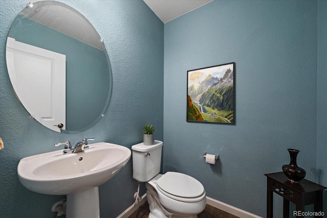 bathroom with baseboards, a sink, wood finished floors, and toilet