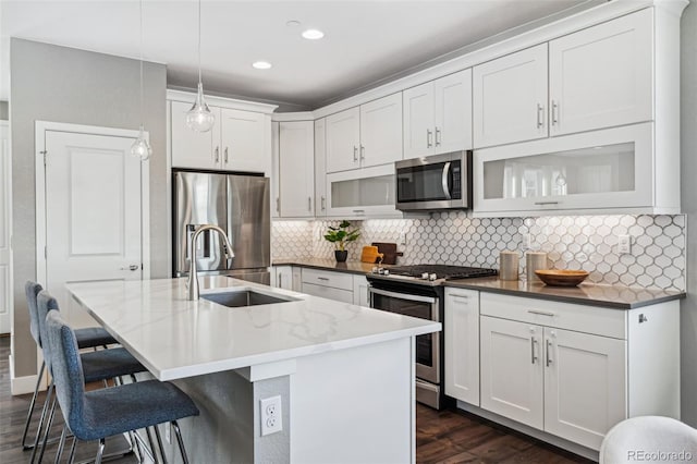 kitchen with dark wood-style floors, a breakfast bar area, stainless steel appliances, decorative backsplash, and a sink