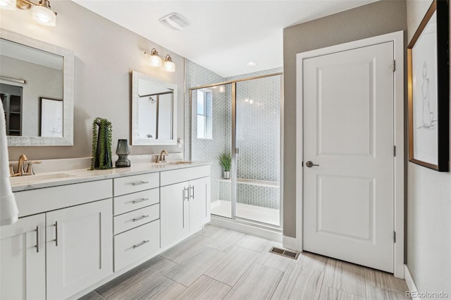 bathroom featuring a stall shower, visible vents, a sink, and double vanity