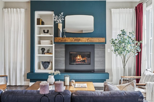 living room with built in shelves, a fireplace, and wood finished floors