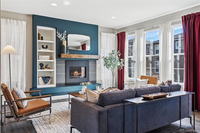 living room featuring recessed lighting, built in features, wood finished floors, and a glass covered fireplace