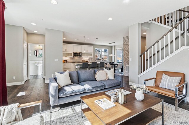 living area with recessed lighting, stairway, wood-type flooring, and baseboards