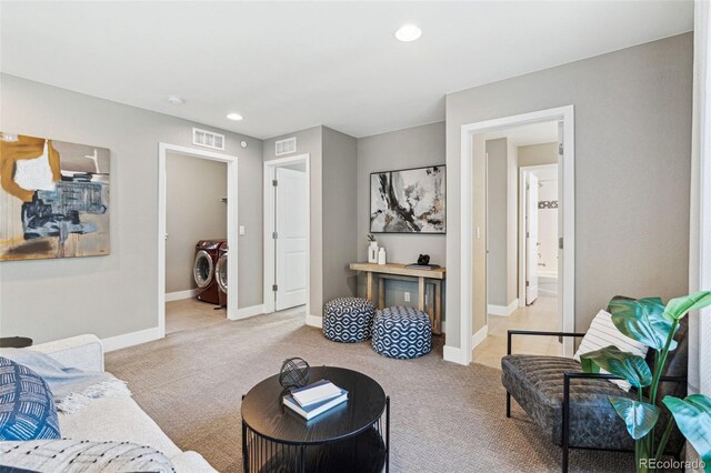 living room with light colored carpet, visible vents, and independent washer and dryer