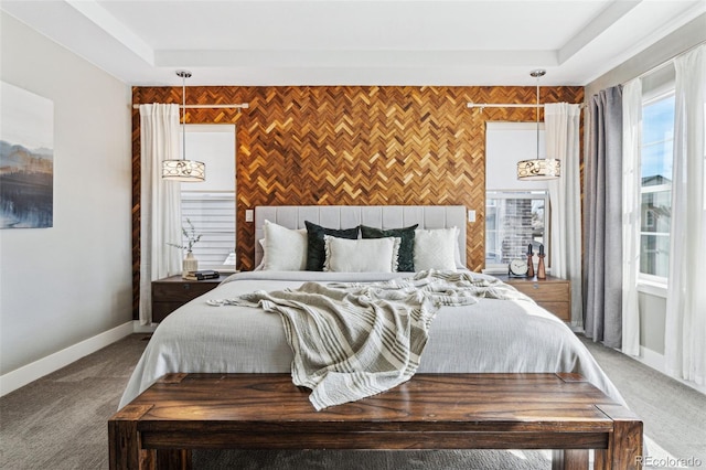 carpeted bedroom featuring an accent wall, baseboards, and a tray ceiling