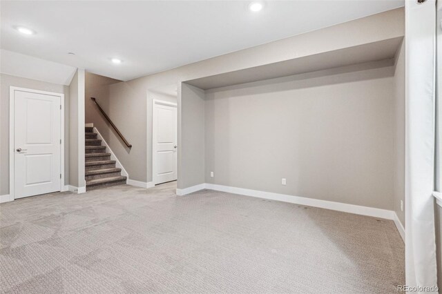 below grade area featuring recessed lighting, light colored carpet, stairway, and baseboards