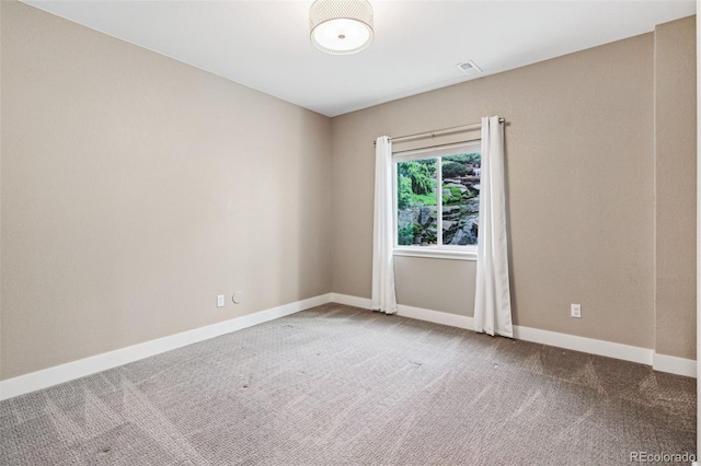 spare room with carpet flooring, visible vents, and baseboards