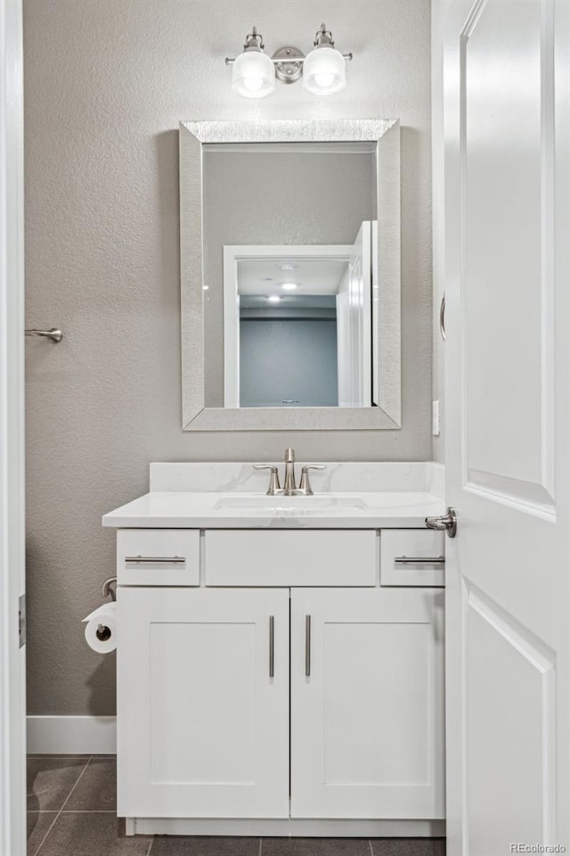 bathroom featuring baseboards, a textured wall, vanity, and tile patterned floors