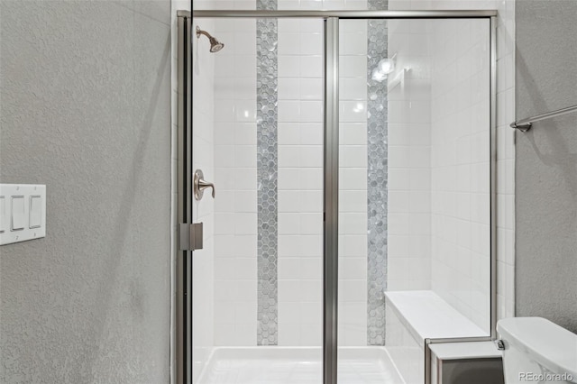 full bath with a stall shower, a textured wall, and toilet