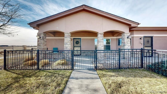 view of front facade featuring a fenced front yard, stone siding, and stucco siding