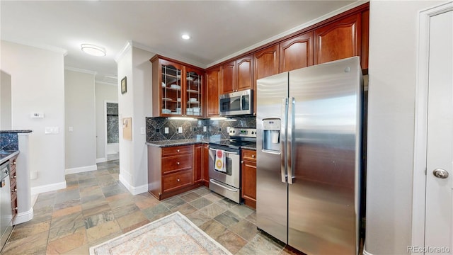 kitchen featuring crown molding, stone tile floors, glass insert cabinets, backsplash, and appliances with stainless steel finishes