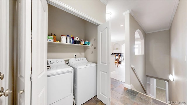 washroom featuring ornamental molding, washing machine and clothes dryer, stone tile flooring, and laundry area