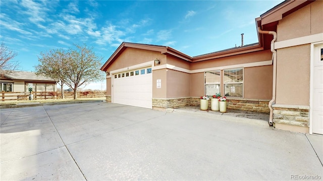 exterior space featuring stone siding, concrete driveway, stucco siding, and a garage