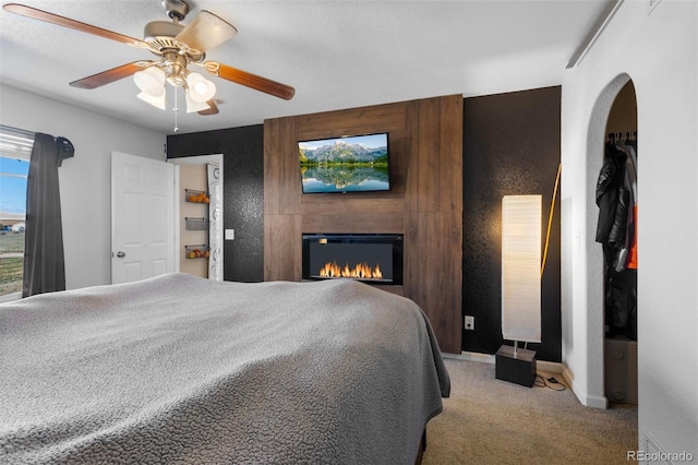 carpeted bedroom with a fireplace and ceiling fan