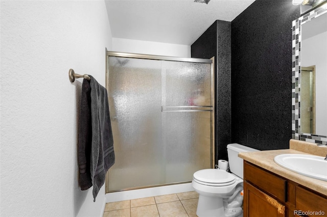 bathroom featuring tile patterned flooring, a shower with shower door, toilet, and vanity