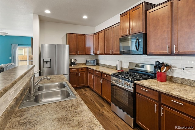 1836 Taos St, Brighton, CO 80603 - kitchen with appliances with stainless steel finishes, a sink, dark wood-style floors, light countertops, and decorative backsplash