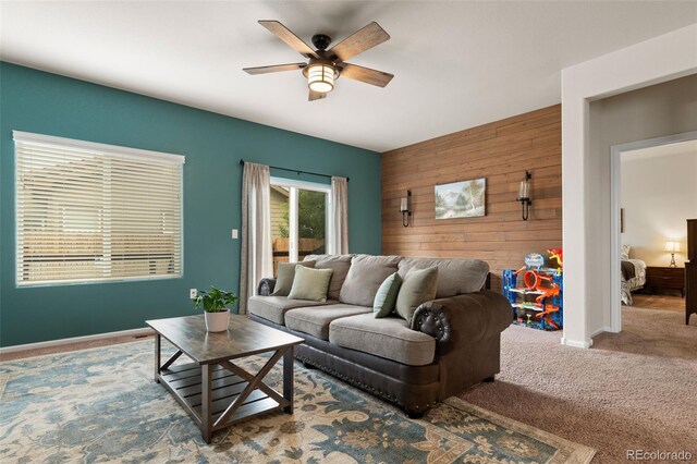 1836 Taos St, Brighton, CO 80603 - carpeted living area featuring wooden walls, ceiling fan, an accent wall, and baseboards