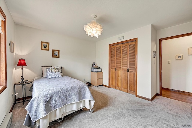 carpeted bedroom featuring a baseboard radiator and a closet