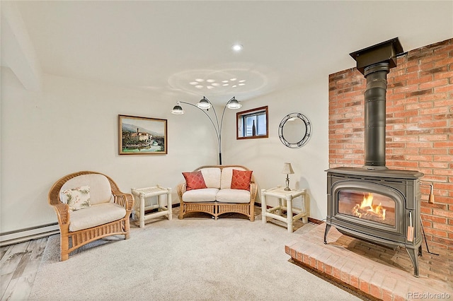 living area with a wood stove, wood-type flooring, baseboard heating, and brick wall