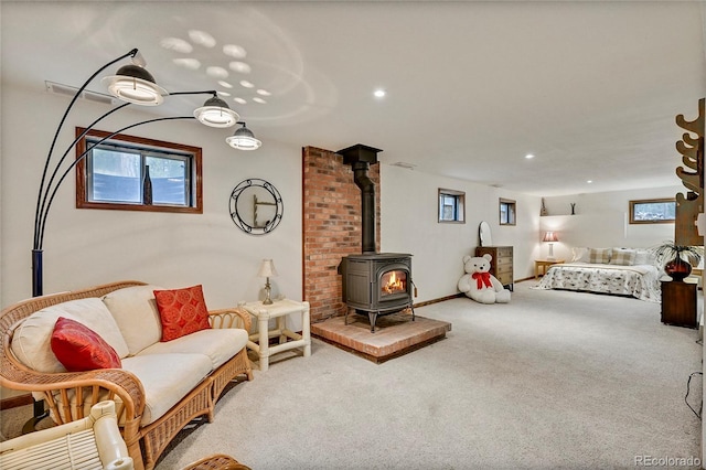 living room with brick wall, carpet flooring, and a wood stove