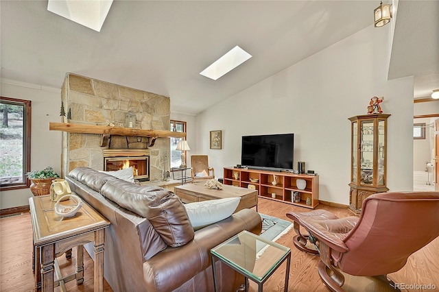 living room featuring a stone fireplace, light hardwood / wood-style floors, and lofted ceiling with skylight