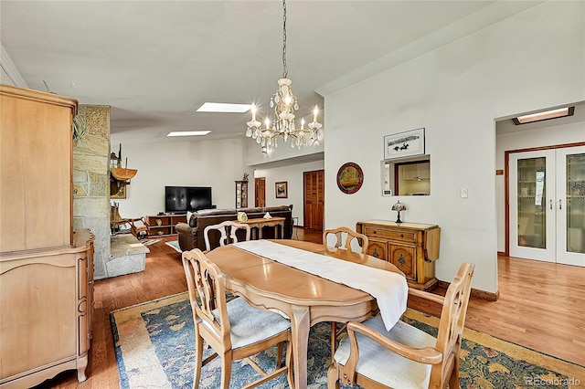 dining room with lofted ceiling, french doors, wood-type flooring, and a notable chandelier