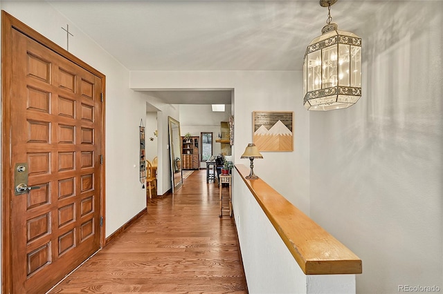 corridor with a notable chandelier and hardwood / wood-style floors