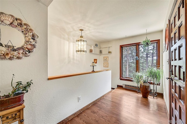 entrance foyer with a chandelier, wood-type flooring, and a baseboard heating unit