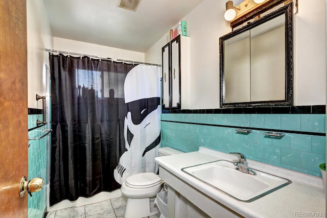 bathroom with tile patterned floors, a shower with curtain, sink, toilet, and tile walls