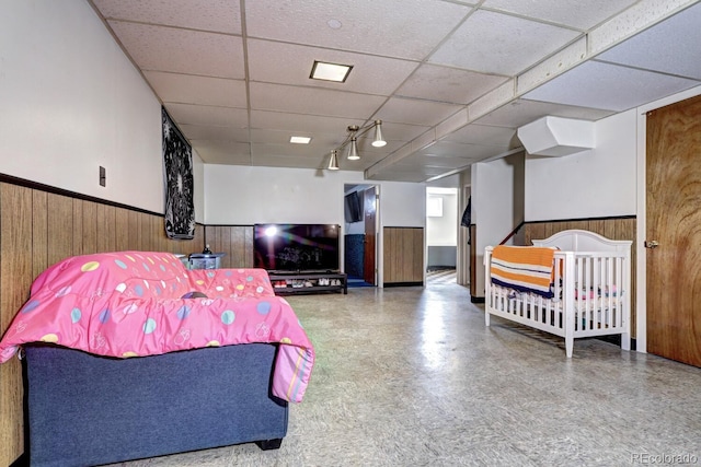 bedroom with a drop ceiling and wood walls