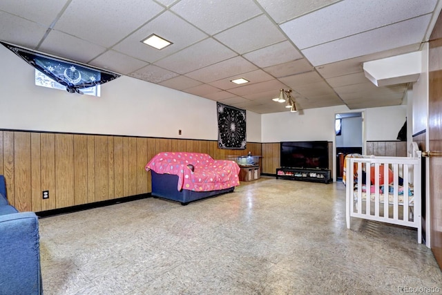 bedroom featuring a paneled ceiling and wooden walls