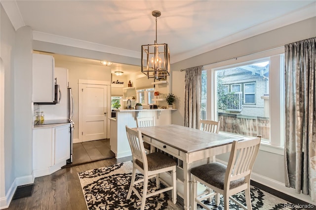 dining space featuring dark hardwood / wood-style flooring, an inviting chandelier, sink, and ornamental molding