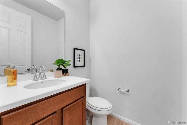 4666 S Malaya Ct, Aurora, CO 80015 - half bathroom featuring vanity, toilet, wood finished floors, and baseboards
