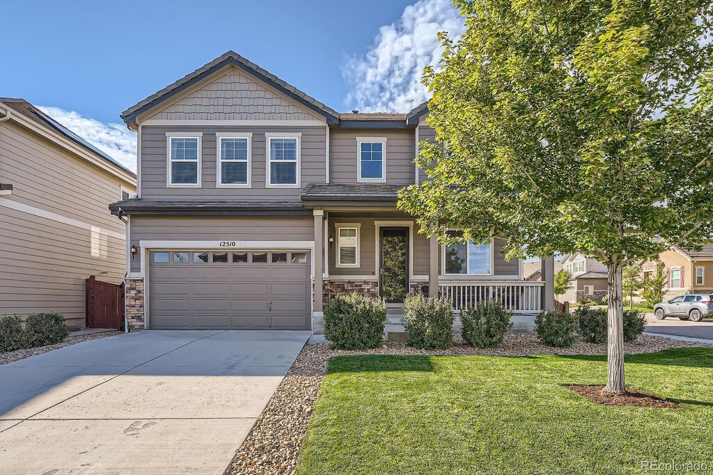 12510 Fisher St, Englewood, CO 80112 - craftsman-style home featuring driveway, an attached garage, covered porch, a front lawn, and stone siding