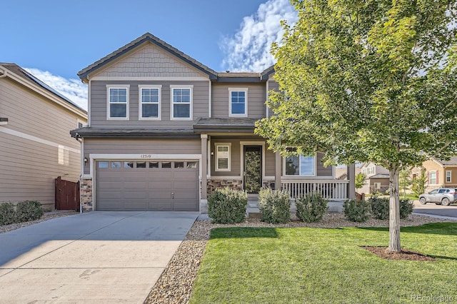 craftsman-style home featuring driveway, an attached garage, covered porch, a front lawn, and stone siding