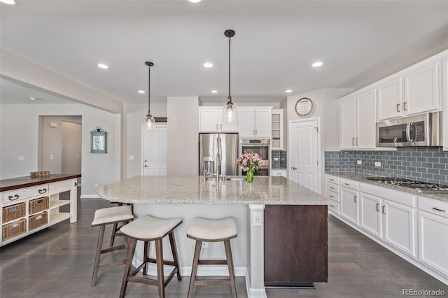 kitchen with backsplash, dark wood finished floors, appliances with stainless steel finishes, white cabinetry, and a sink