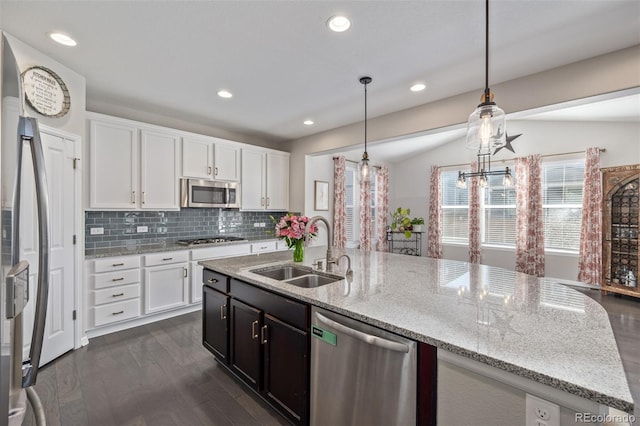 kitchen with a sink, dark wood-style floors, white cabinetry, appliances with stainless steel finishes, and decorative backsplash