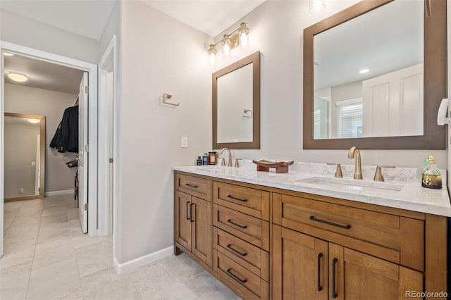 full bath with double vanity, baseboards, and a sink