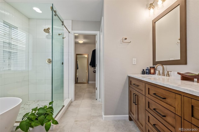 full bathroom with vanity, a shower stall, a freestanding tub, and baseboards