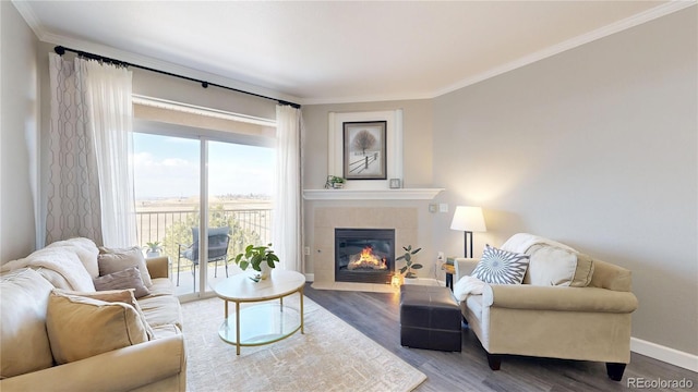 living room with a tile fireplace, baseboards, crown molding, and wood finished floors