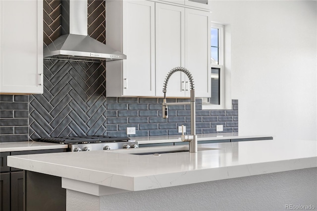 kitchen featuring white cabinetry, backsplash, and wall chimney range hood