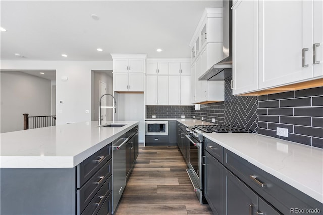 kitchen featuring sink, dark wood-type flooring, an island with sink, stainless steel appliances, and white cabinets