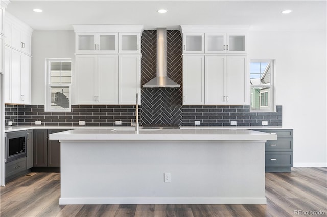 kitchen featuring white cabinets, wall chimney range hood, dark hardwood / wood-style flooring, gray cabinetry, and built in microwave