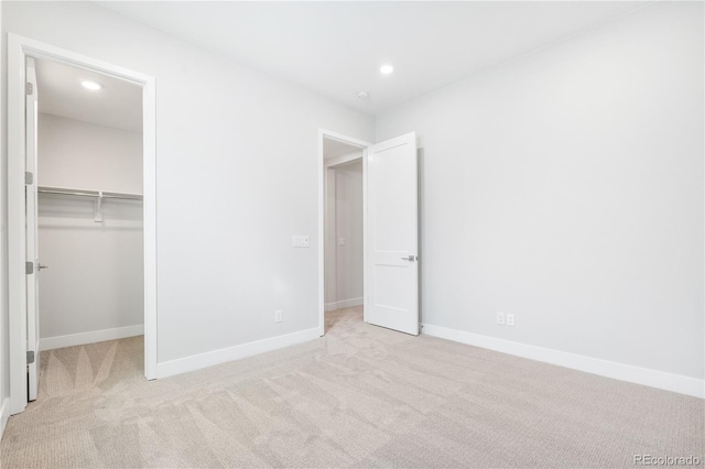 unfurnished bedroom featuring a closet, a walk in closet, and light colored carpet