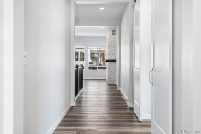 hall with a barn door and dark hardwood / wood-style floors